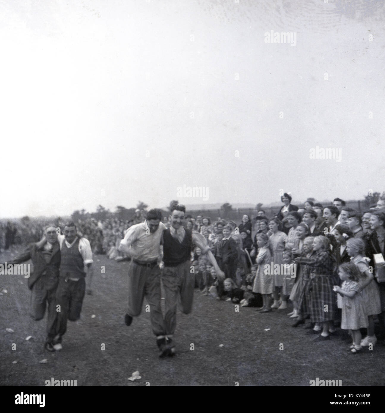 1951, storico, una atmosfera di carnevale come spettatori godetevi un quattro completamente vestito di uomini in esecuzione in un tripiede di gara come parte del Festival della Bretagna celebrazioni. Foto Stock