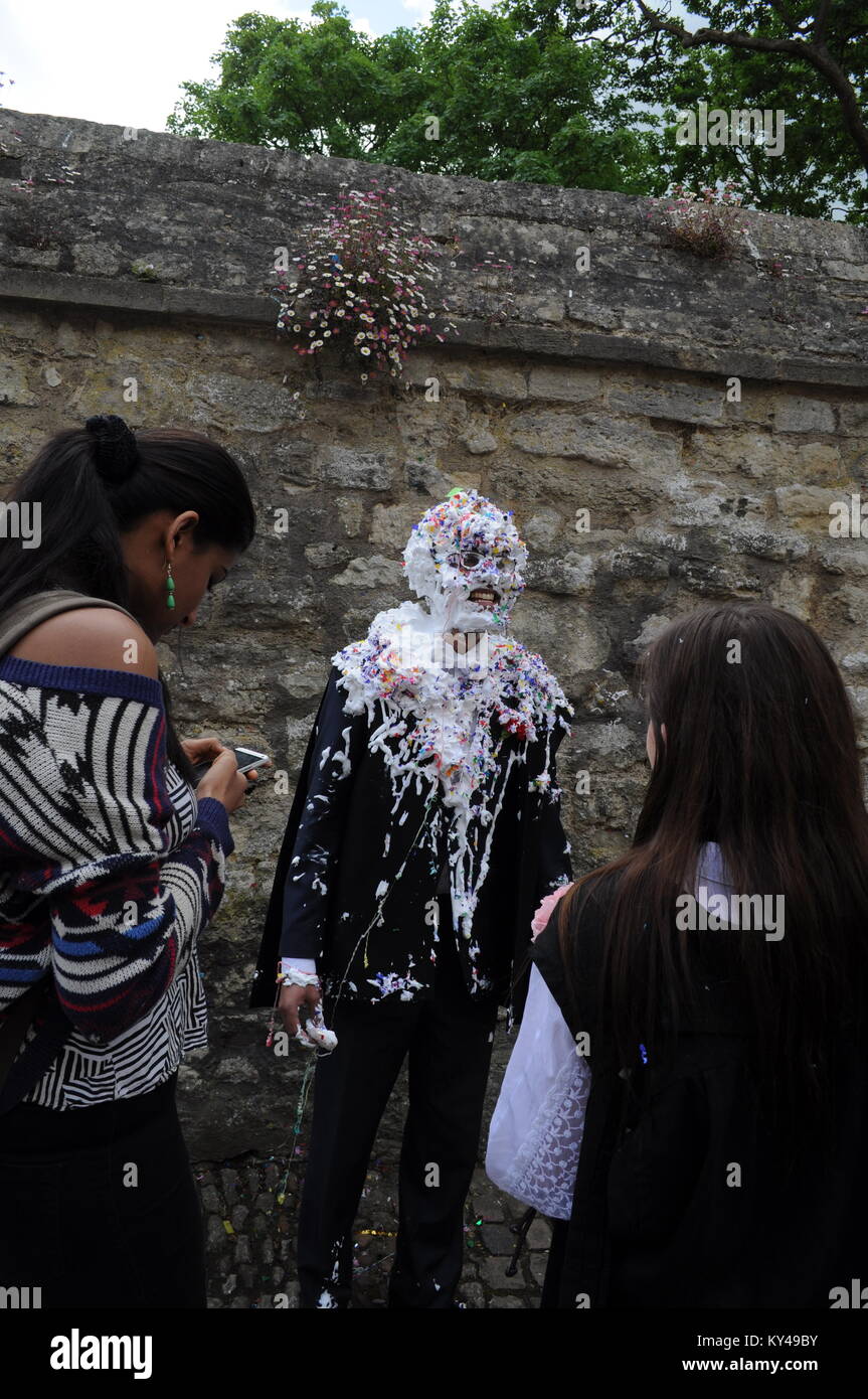 Studenti che lasciano il loro ultimo esame per incontrare gli amici per un tradizionale "distruggendo' sul retro dell Università di Oxford Scuola di esame, Oxford, Inghilterra, Regno Unito. Foto Stock