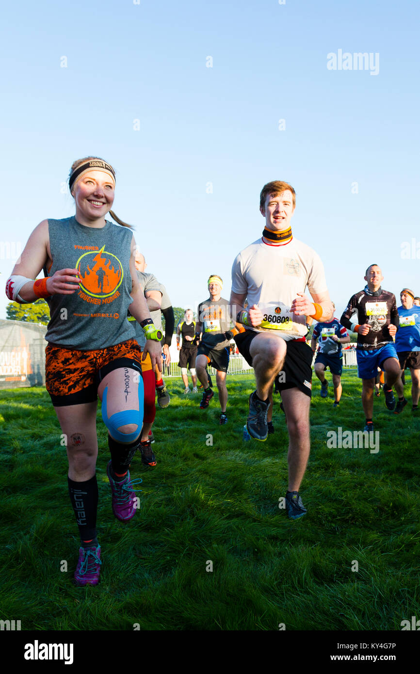 Sussex, Regno Unito. Un uomo e una donna sorriso come si scaldano davanti a un duro Mudder evento. Foto Stock