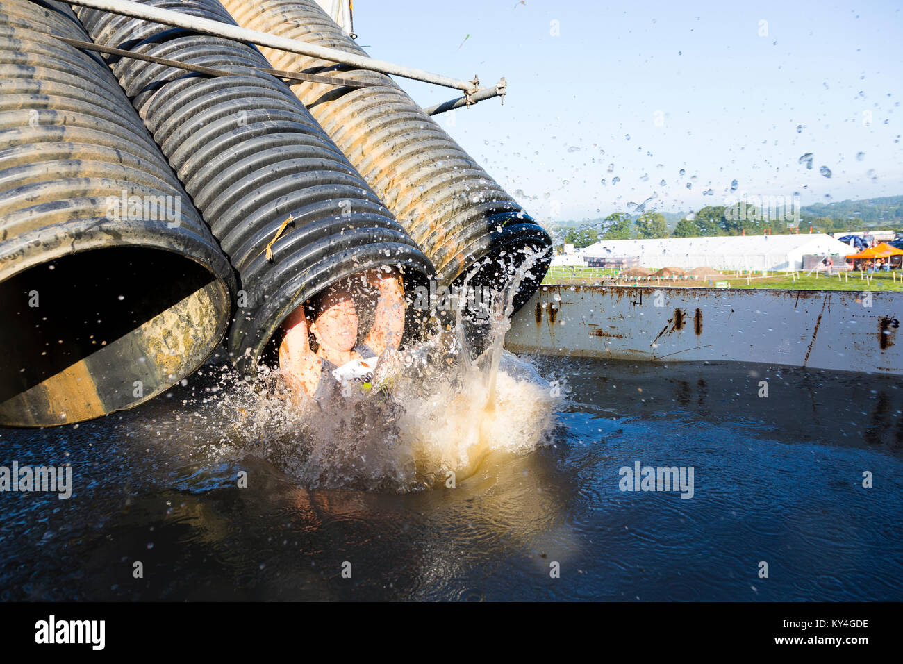 Sussex, Regno Unito. Una giovane donna chiude gli occhi come lei cade in una grande piscina piena di acqua gelida durante una dura Mudder evento. Foto Stock
