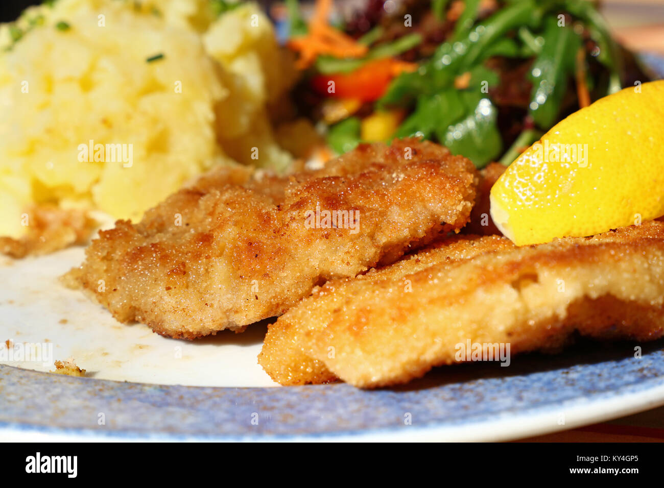 Vicino la porzione del Wiener Schnitzel con patate, insalata e limone su tavolo, a basso angolo di visione Foto Stock