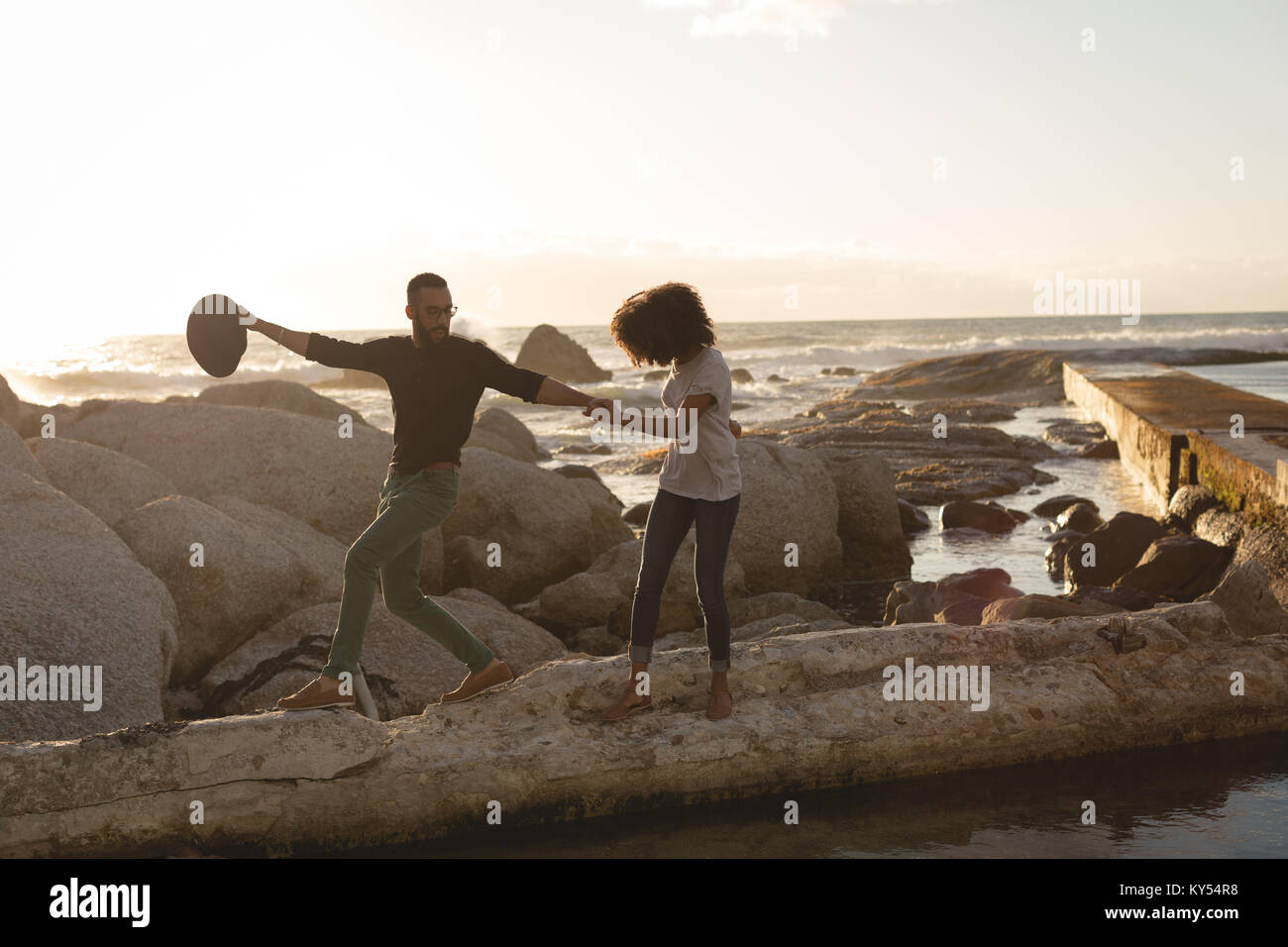 Giovane a camminare su una roccia nei pressi di una spiaggia Foto Stock