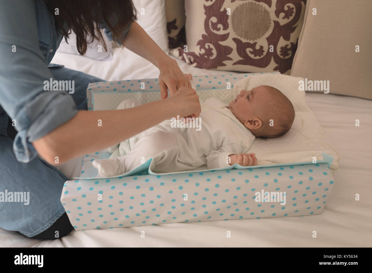 Carino piccolo bambino di vestirsi da sua madre sul letto in camera da letto Foto Stock