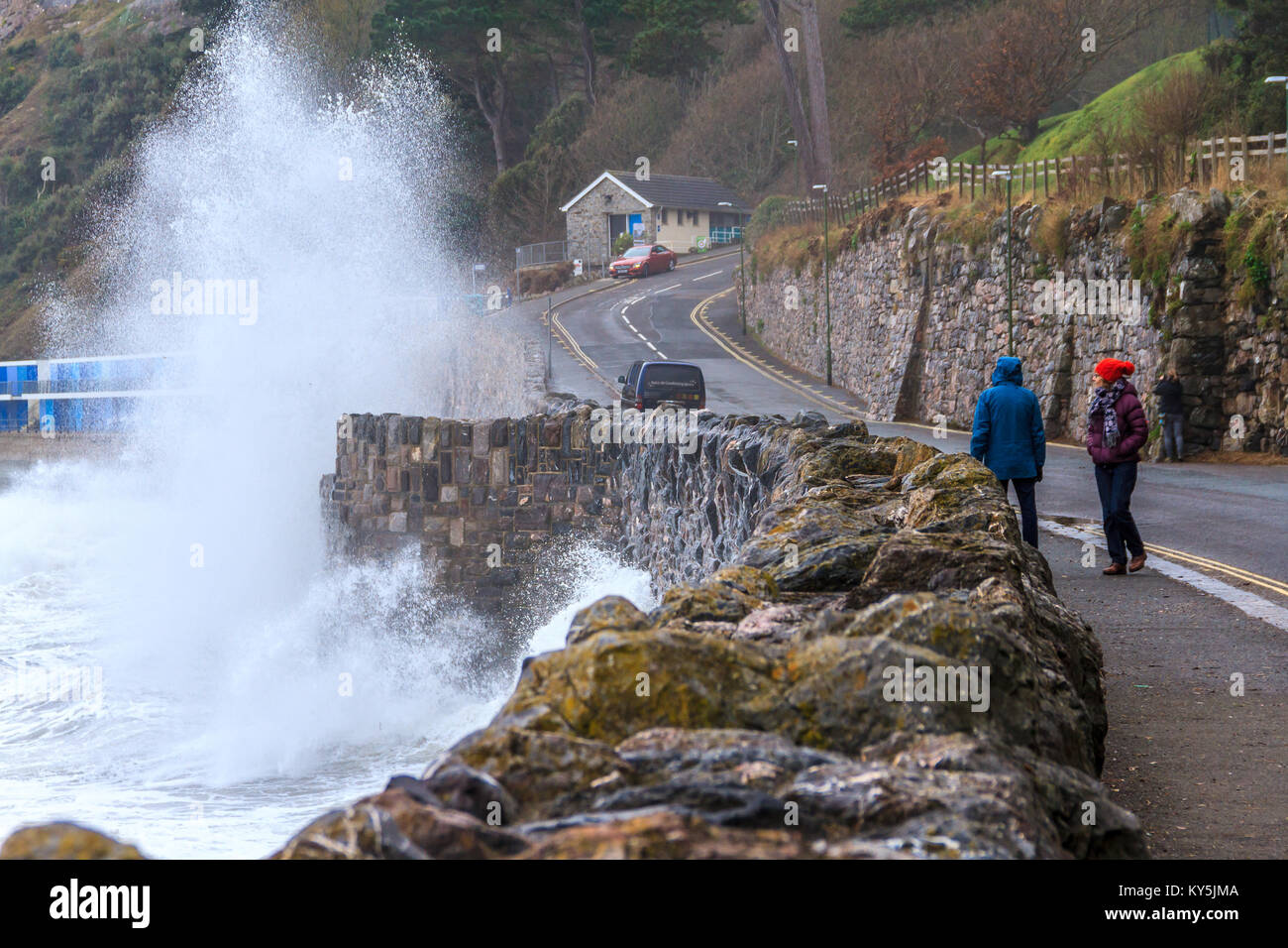 I passanti da guardare la violazione delle onde del mare a parete Meadfoot Beach in Torquay, Torbay, Devon, Regno Unito. Gennaio 2018. Foto Stock