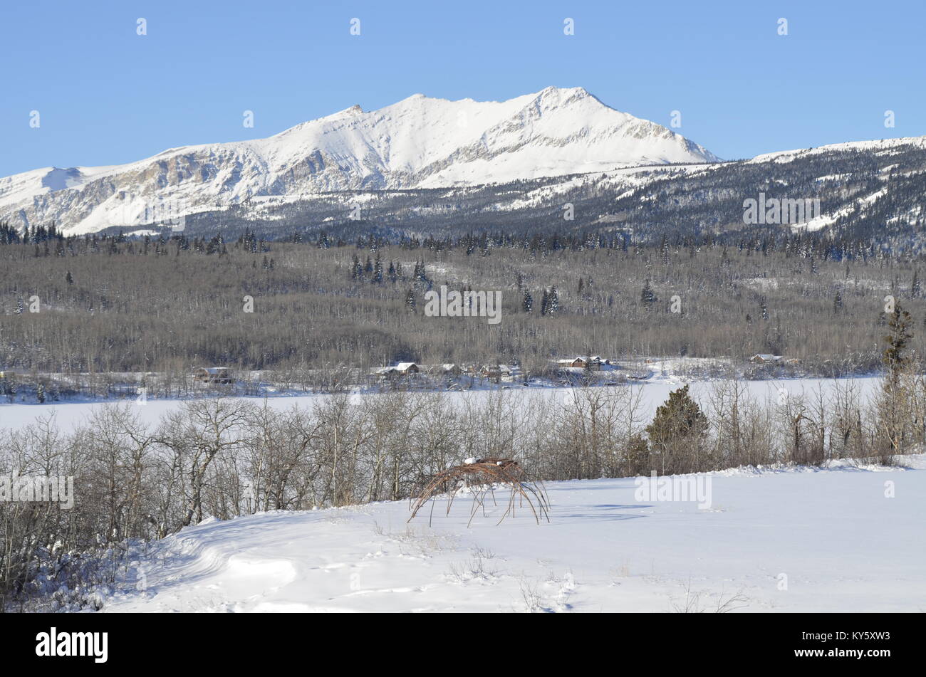 Lo scheletro di due logge di sudore sedersi in una coperta di neve campo con una magnifica montagna e lago vista di sfondo Foto Stock