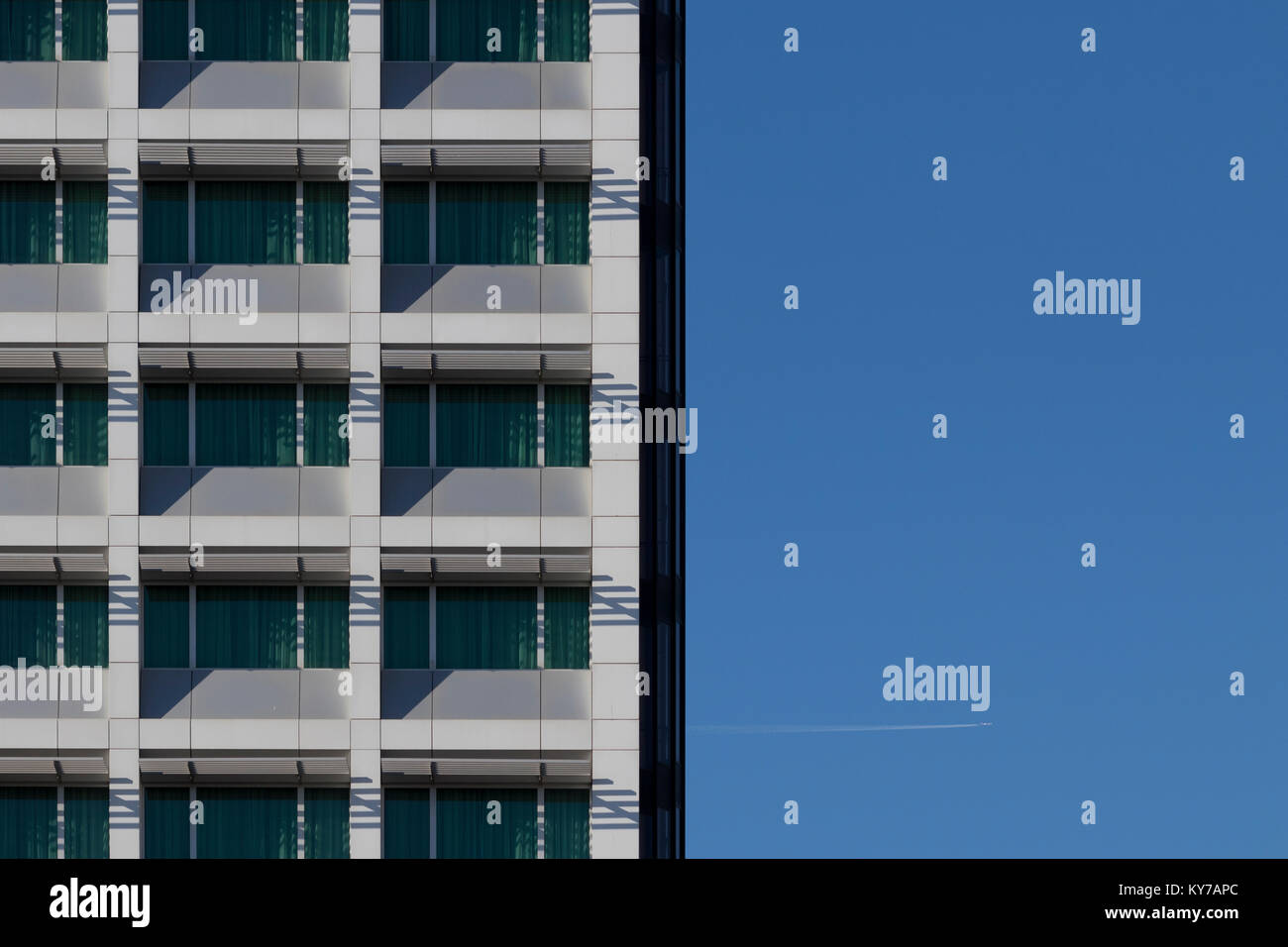 Immagine di sfondo di un cielo blu con un edificio di uffici facciata ed un sentiero bianco da un piano nel cielo. Foto Stock