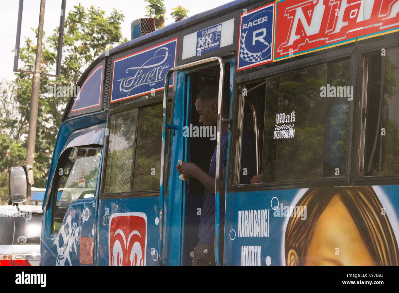 Un conduttore di bus si erge nel bus porta conteggiare denaro, Nairobi, Kenya, Africa orientale Foto Stock