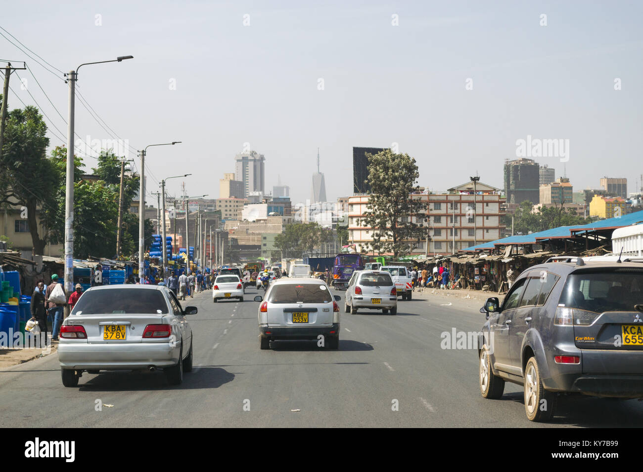 Veicoli in movimento verso il basso Ring Road Ngara con bancarelle e negozi sul ciglio della strada e la gente che cammina, Nairobi, Kenya, Africa orientale Foto Stock