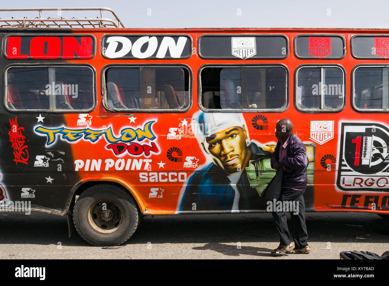 Un uomo cammina passato un decorate luminosamente bus con un dipinto di 50 cent sul lato, Nairobi, Kenya, Africa orientale Foto Stock