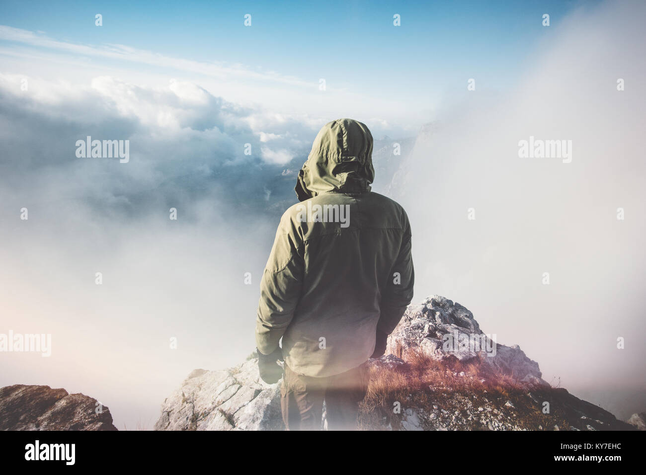 L'uomo Traveler in piedi sul vertice di montagna con nuvole attorno a uno stile di vita viaggio concetto di successo avventura vacanze attive outdoor vista posteriore Foto Stock