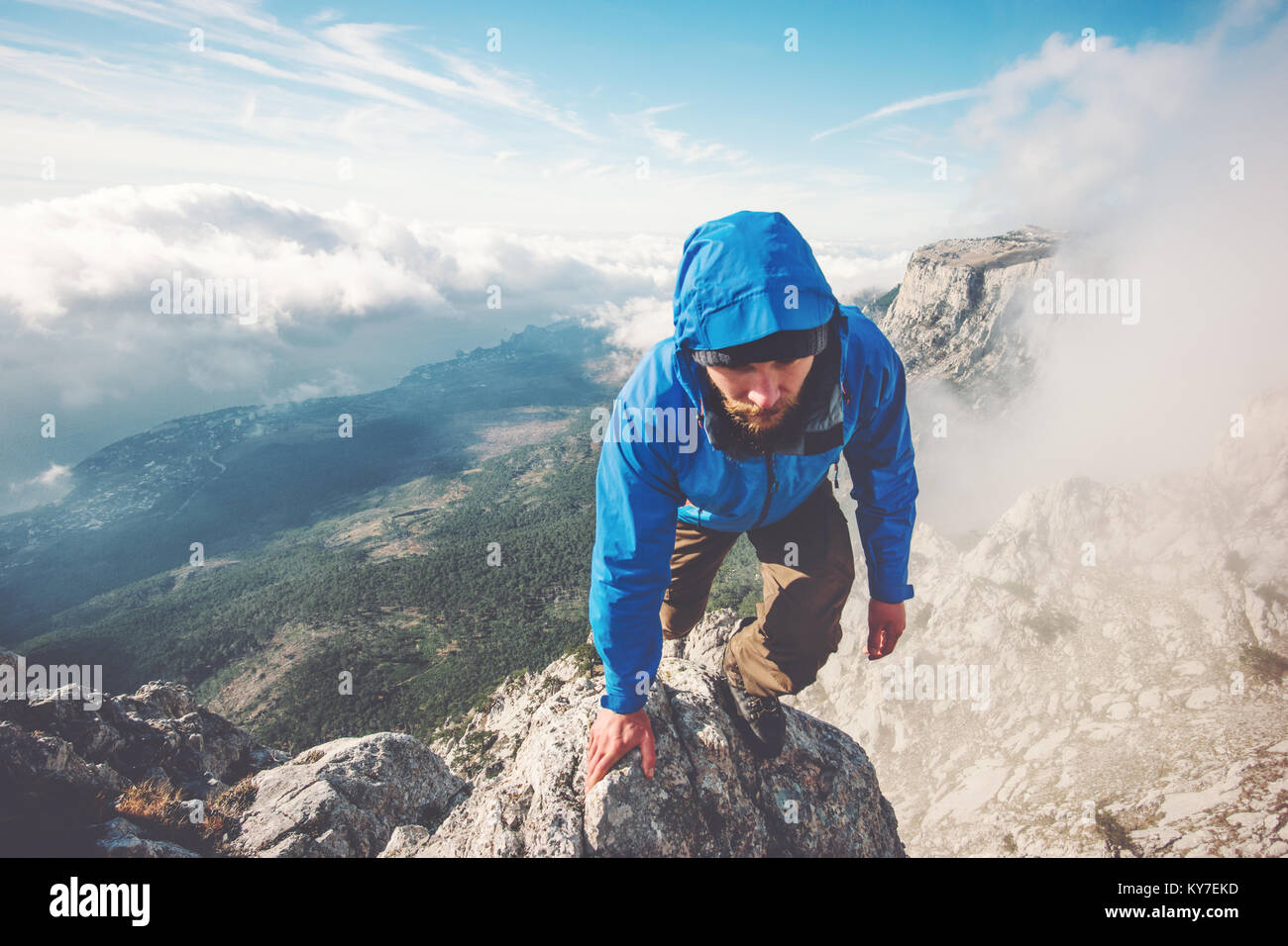 L'uomo Traveler arrampicata sul vertice di montagna sopra le nuvole stile di vita viaggio concetto di successo avventura vacanze attive outdoor sport estremi Foto Stock