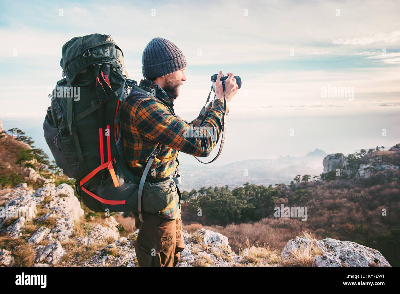 L'uomo fotografo con zaino e fotocamera prendendo foto di montagne stile di vita viaggio concetto hobby Vacanze avventura all'aperto Foto Stock
