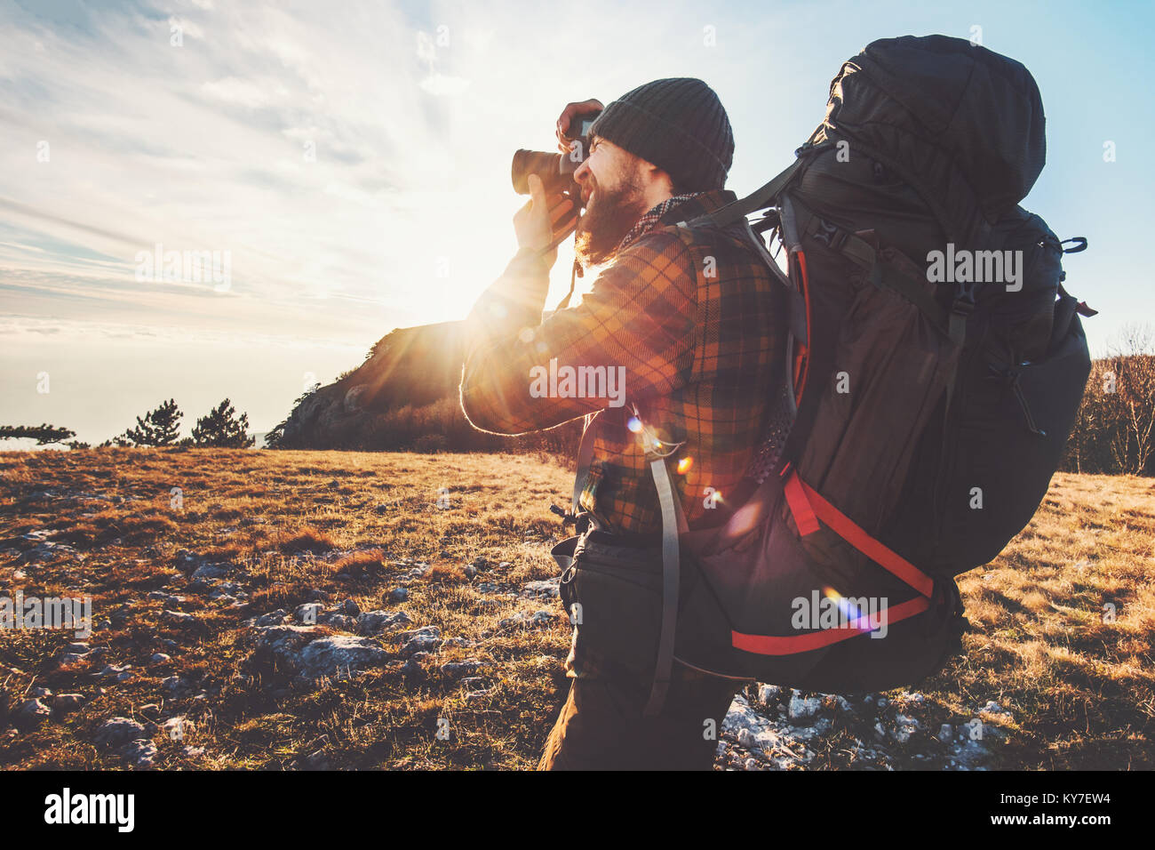 L'uomo fotografo con grande zaino e fotocamera tenendo la foto del tramonto montagne stile di vita viaggio concetto hobby avventura vacanze attive outdoor Foto Stock