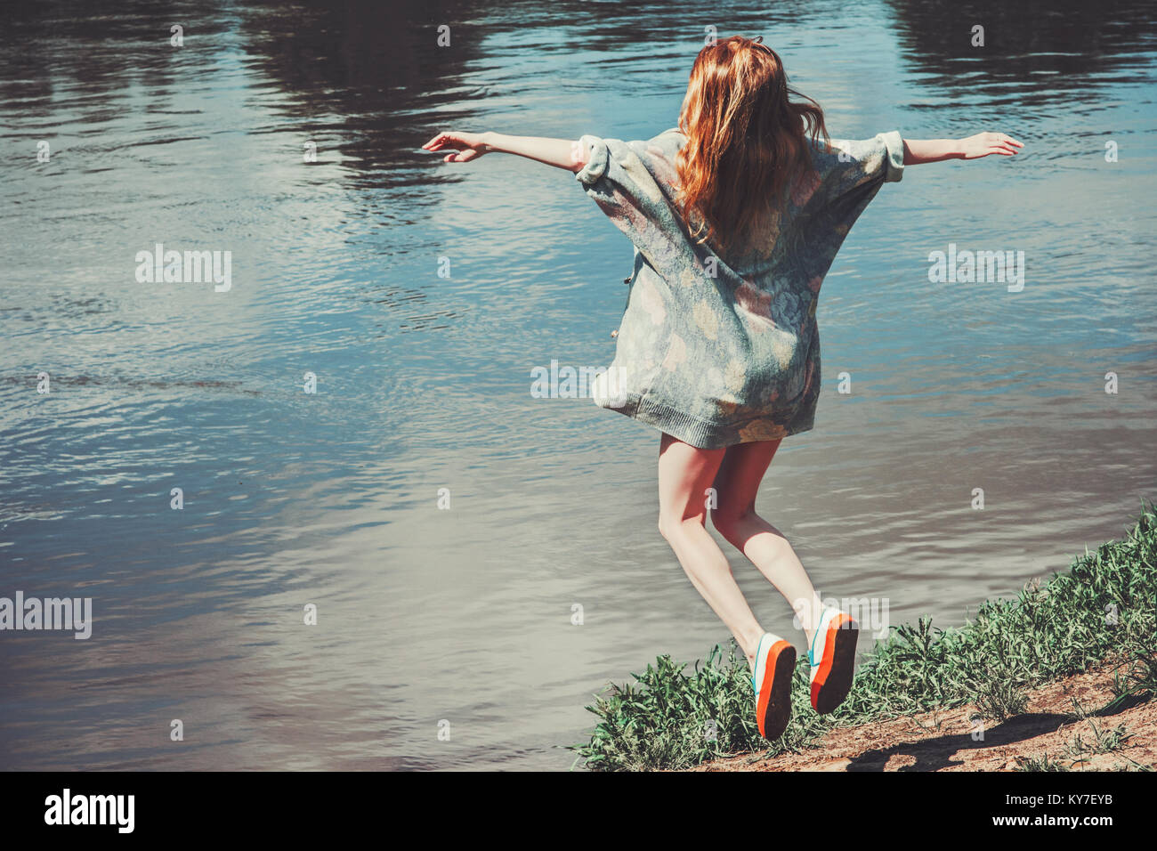 Donna felice il salto battenti levitazione paesaggio fluviale sullo sfondo dello stile di vita le emozioni di viaggio il concetto di successo all'aperto le mani alzate Foto Stock