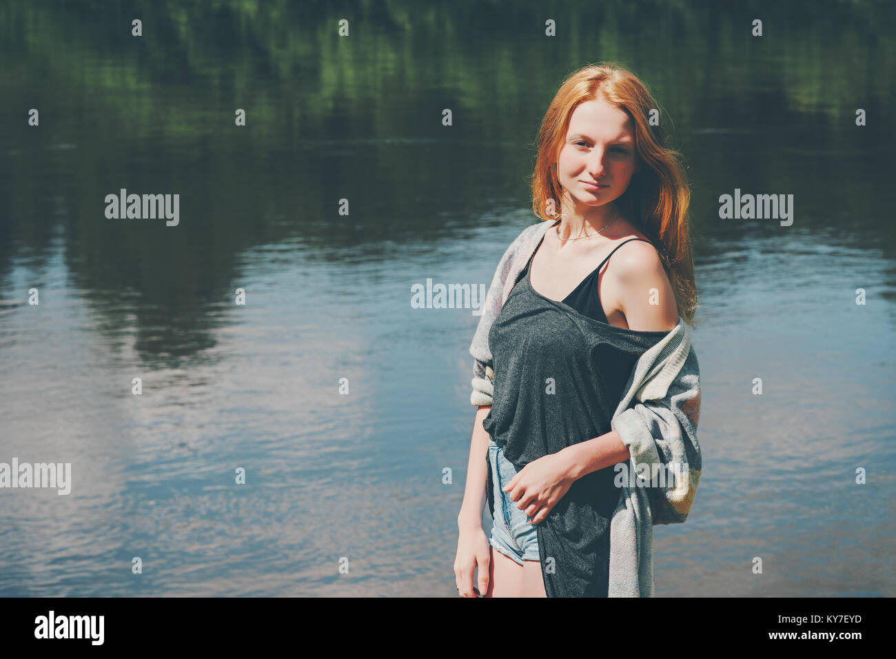 Bella ragazza camminare al fiume Lifestyle vacanze estive in armonia con la  natura del concetto. Giovane donna con i capelli rossi che indossa jeans  corti e top moda casual Foto stock -
