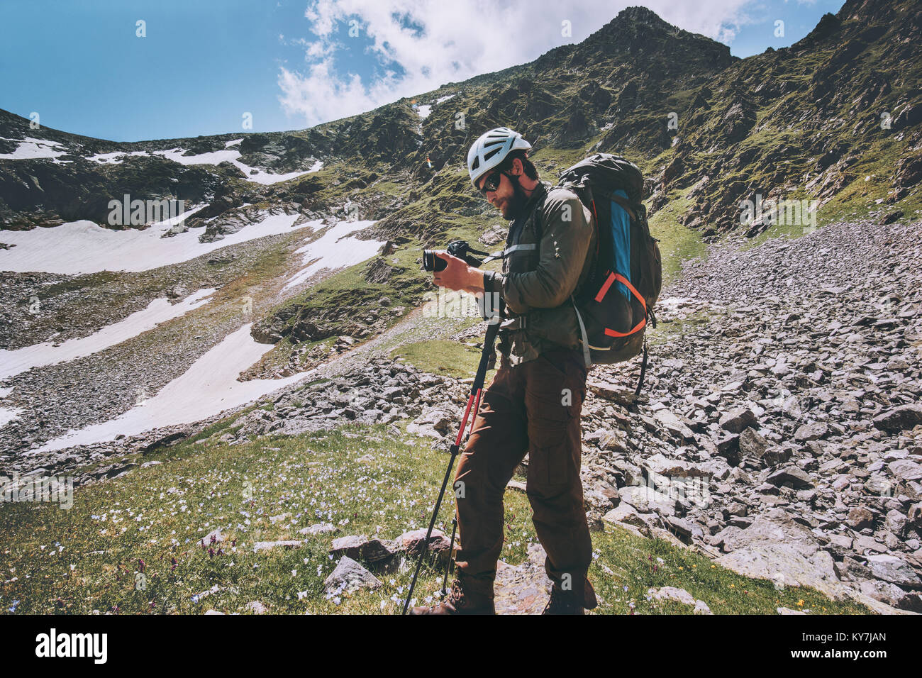 L'uomo fotografo con zaino trekking in montagna lo stile di vita di viaggio adventure concept vacanze estive all'aperto esplorando la natura selvaggia che indossa il casco Foto Stock