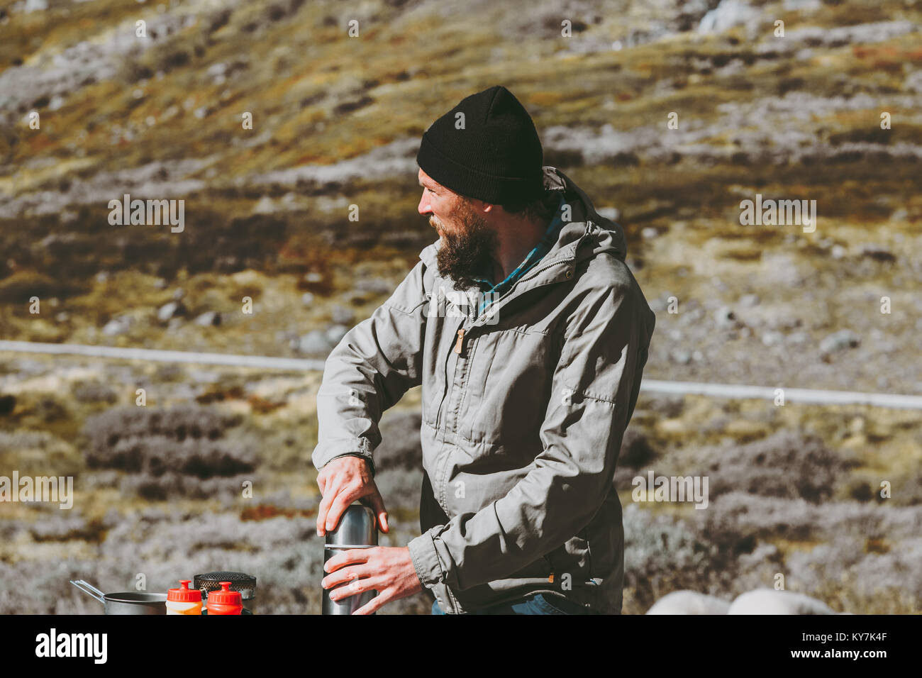 L'uomo traveler holding thermos di sopravvivenza in montagna stile di vita viaggio concetto di sopravvivenza vacanze nel selvaggio Foto Stock