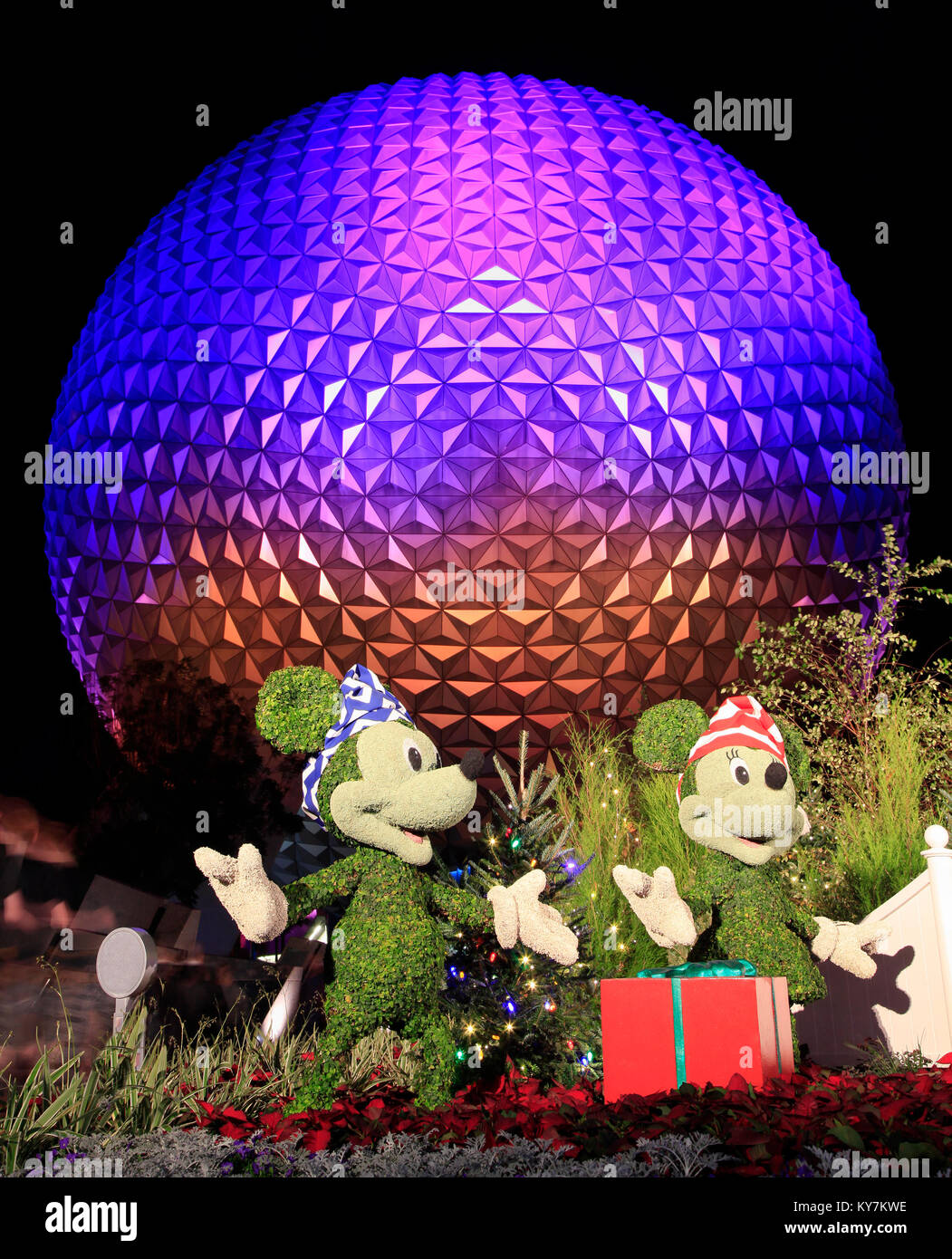 Disney's Epcot Center sfera illuminata di notte durante la stagione di vacanze con Topolino e Minnie e Plutone caratteri erba sculture sul foregr Foto Stock