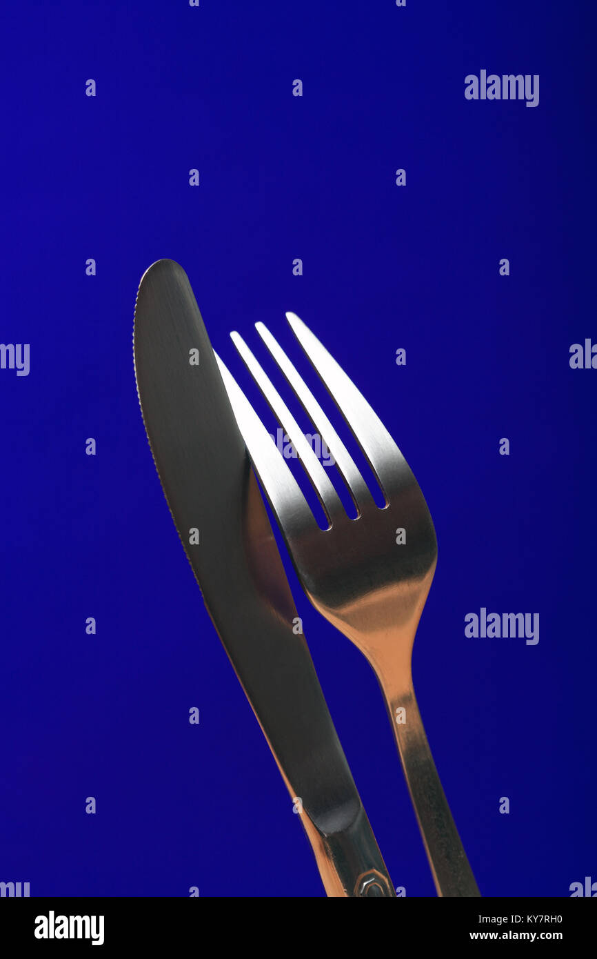Extreme closeup di forchetta e coltello da tavola su sfondo blu Foto Stock
