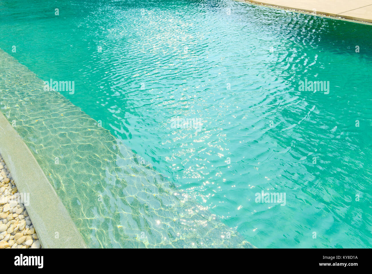 Primo piano della frontiera di pietra di fronte blu brillante piscina. La decorazione e la progettazione di piscine con luce solare, vacanza, relax, getaway concep Foto Stock