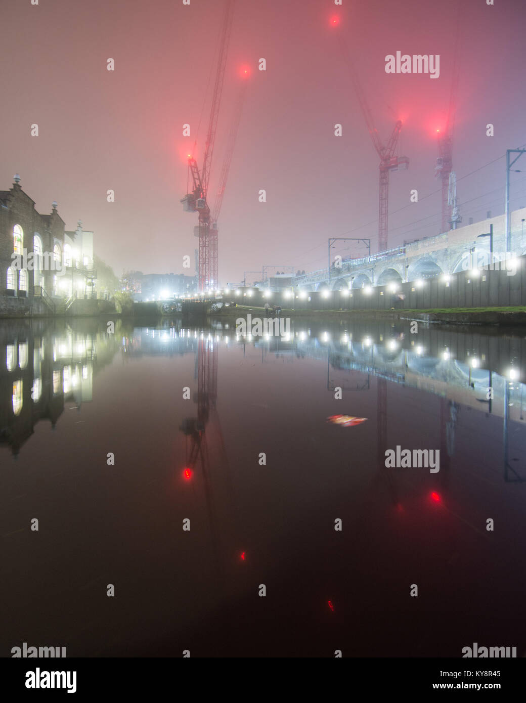 London, England, Regno Unito - 30 dicembre 2016: magazzini, gru a torre e la North London Linea ferroviaria sono riflesse nel Regent's Canal tra Kentis Foto Stock
