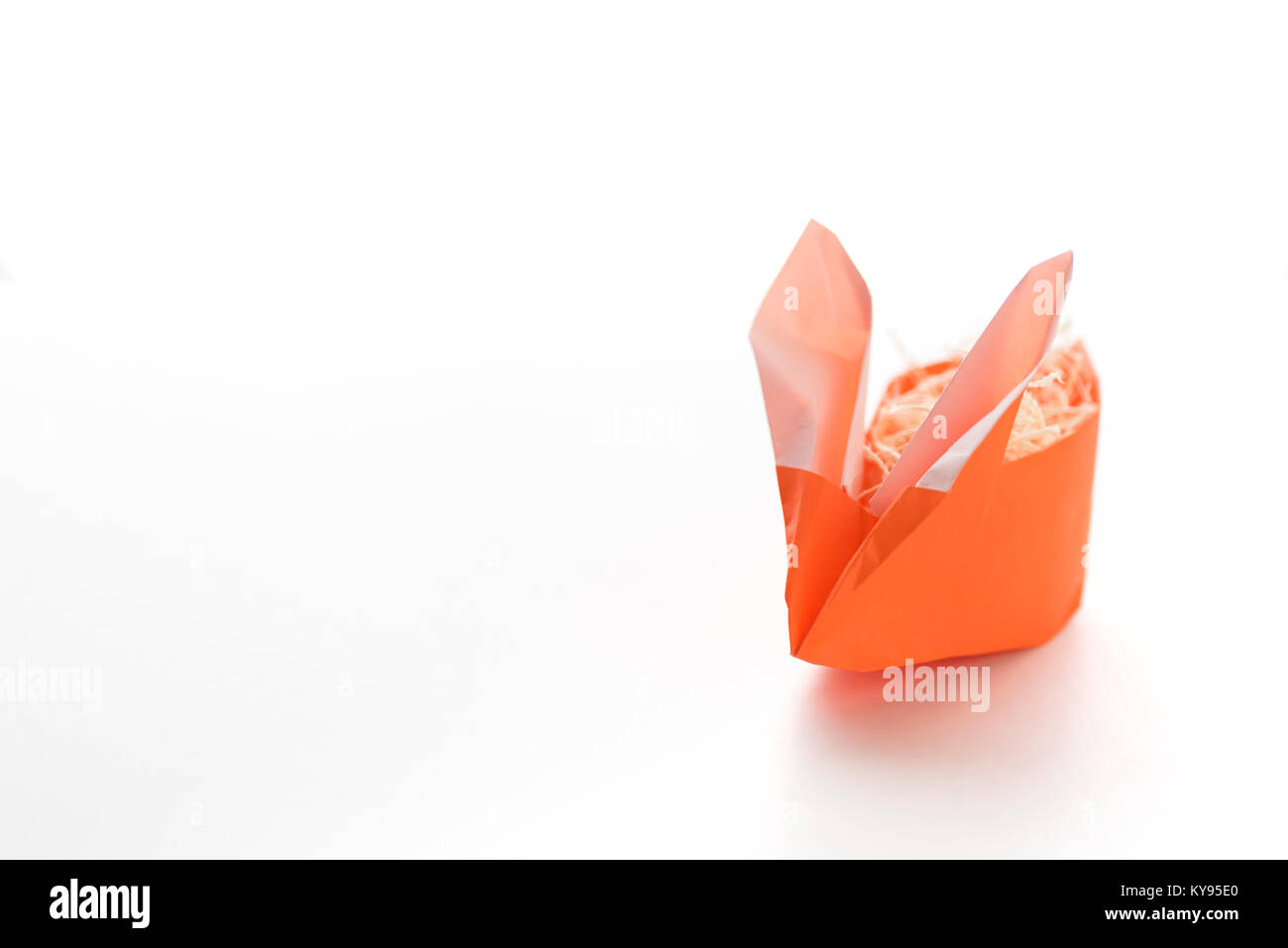 Uno colorato arancione origami Easter Bunny rabbit fatta di carta ripieni di paglia, pronto per l'uovo di pasqua, isolati su sfondo bianco Foto Stock