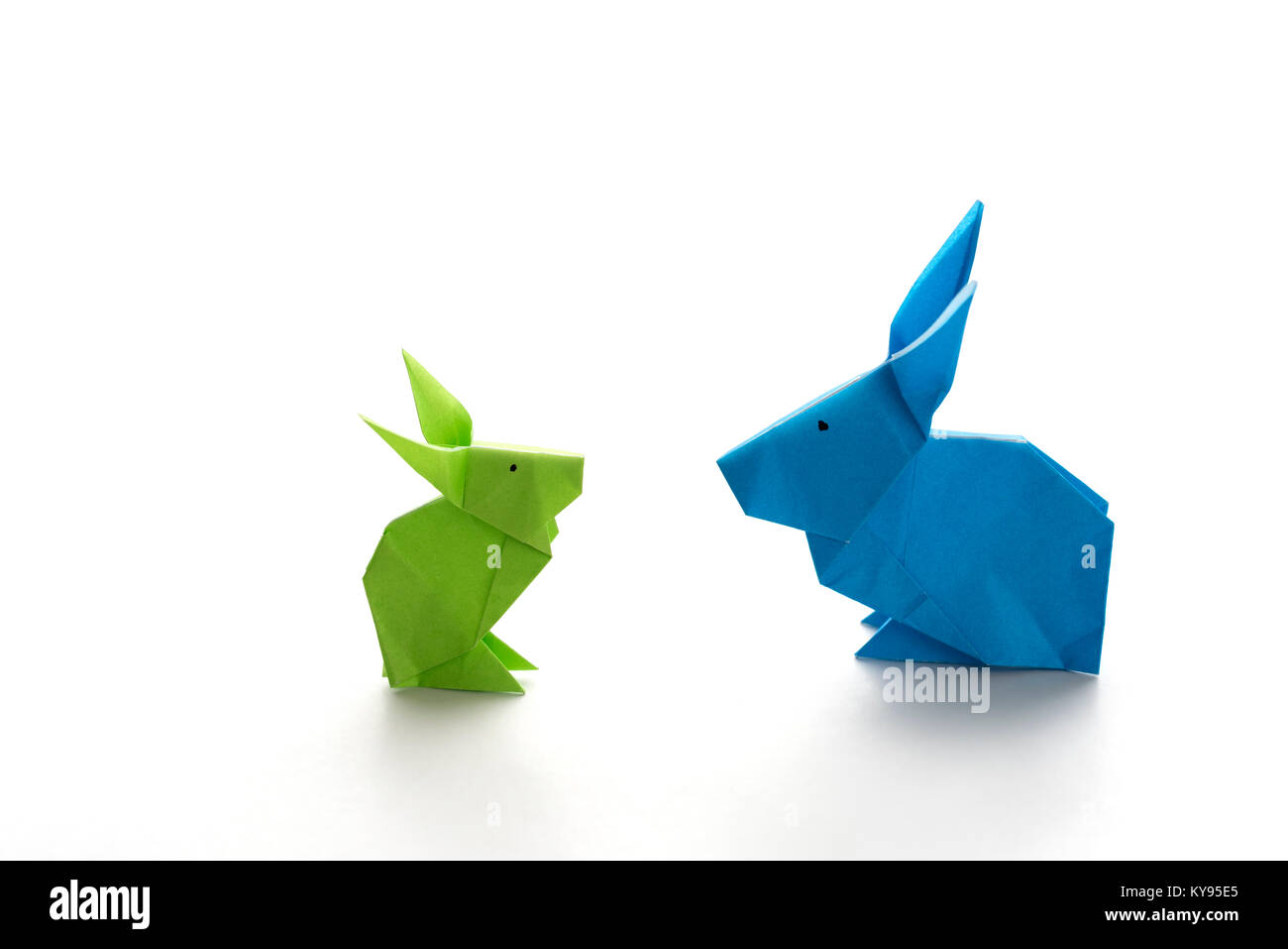 Due coloratissimi origami coniglietto di pasqua conigli fatta di carta in verde e blu, di diverse dimensioni, forse genitore e bambino per quanto riguarda ogni altro, pronto per Foto Stock