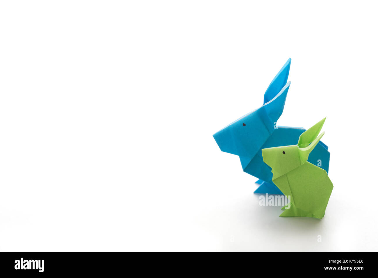 Due coloratissimi origami coniglietto di pasqua conigli fatta di carta in verde e blu, di diverse dimensioni, forse genitore e bambino in piedi a fianco a fianco, pronto fo Foto Stock