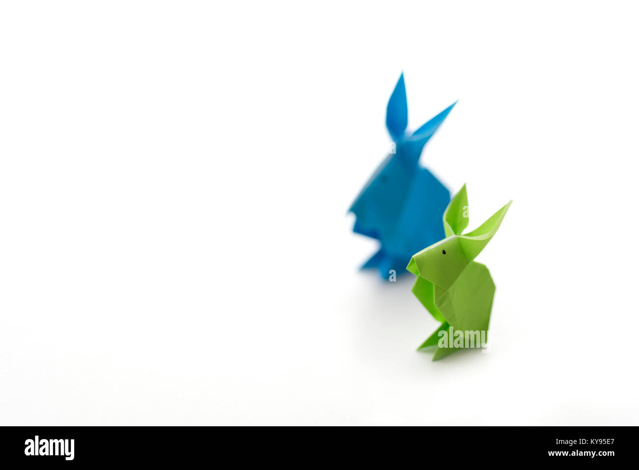Due coloratissimi origami coniglietto di pasqua conigli fatta di carta in verde e blu, di diverse dimensioni, forse genitore e bambino in piedi a fianco a fianco, pronto fo Foto Stock