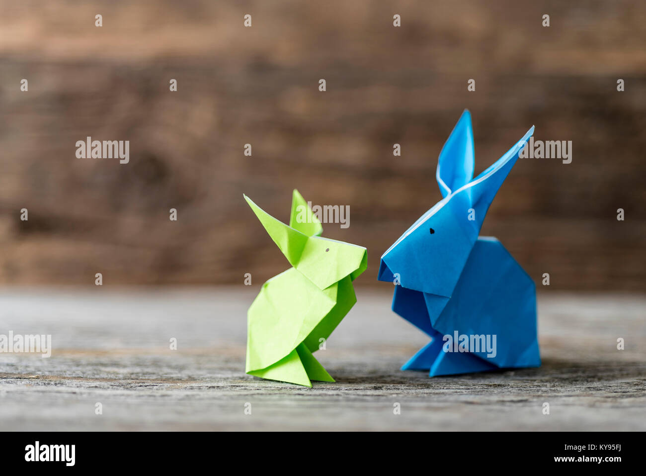 Due coloratissimi origami coniglietto di pasqua conigli fatta di carta in verde e blu, di diverse dimensioni, forse genitore e bambino per quanto riguarda ogni altro, pronto per Foto Stock