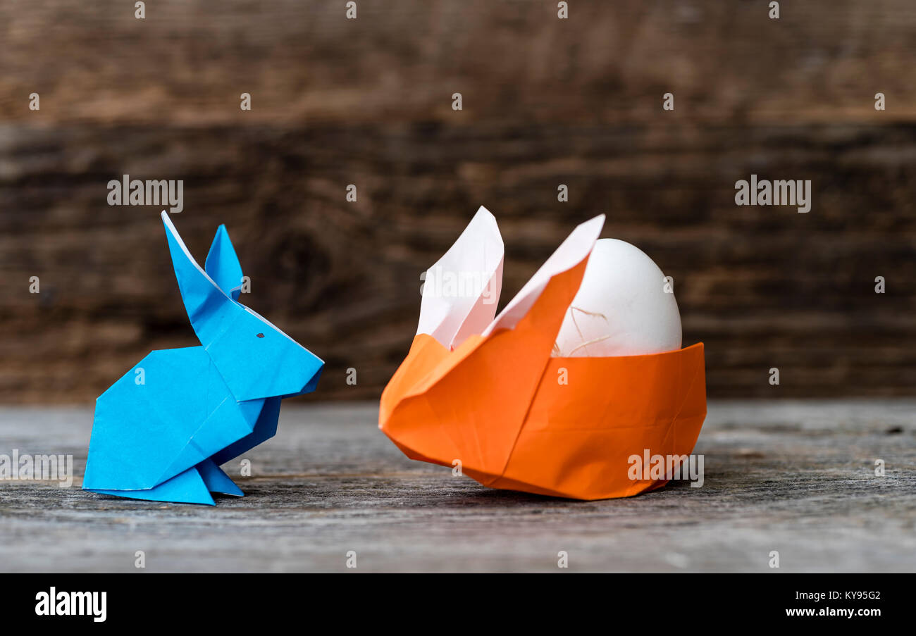 Due coloratissimi origami coniglietto di pasqua conigli fatta di carta in  arancione e blu, di diverse dimensioni, forse genitore e bambino con uovo  cullata dal colore arancione Foto stock - Alamy