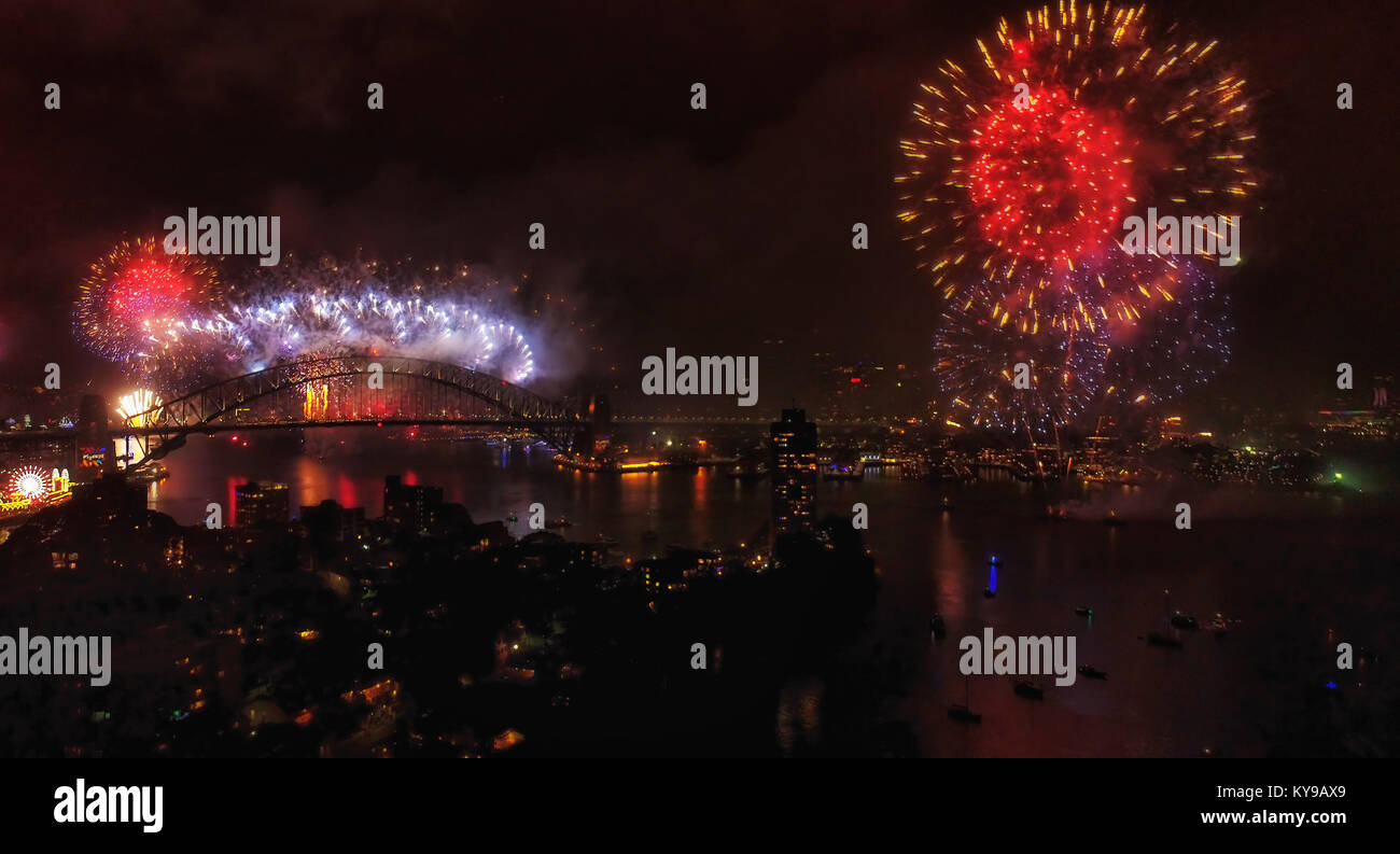 Notte oscura alla vigilia di Capodanno 2018 a Sydney nel corso annuale di fuochi d'artificio cotta su pietre miliari australiano e il CBD di Città con il Ponte del Porto di Sydney che riflette i Foto Stock