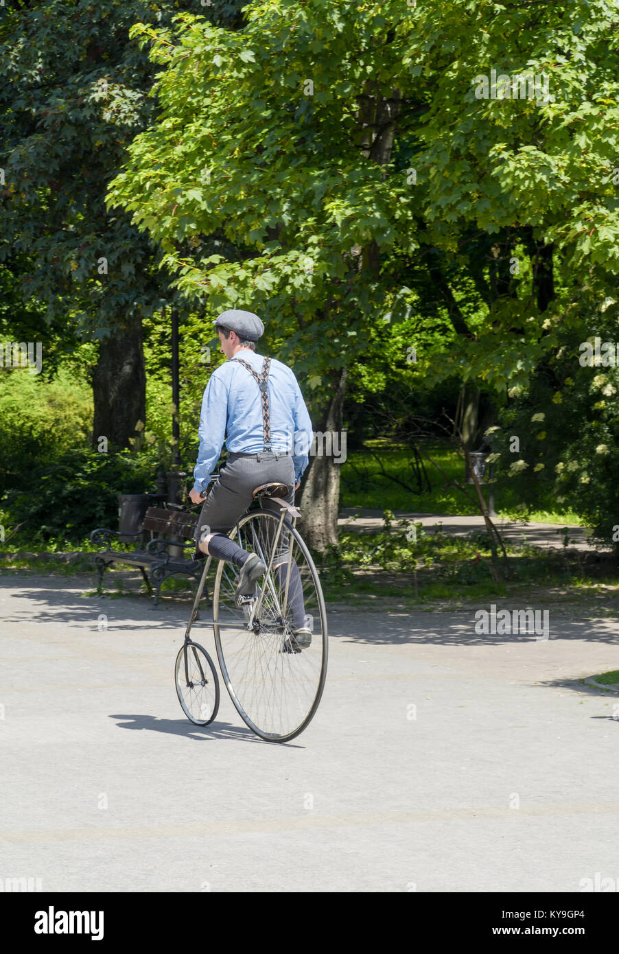 Giovane ciclista vestito in un vecchio stile vestiti corre sul suo american star tipo bicicletta Foto Stock