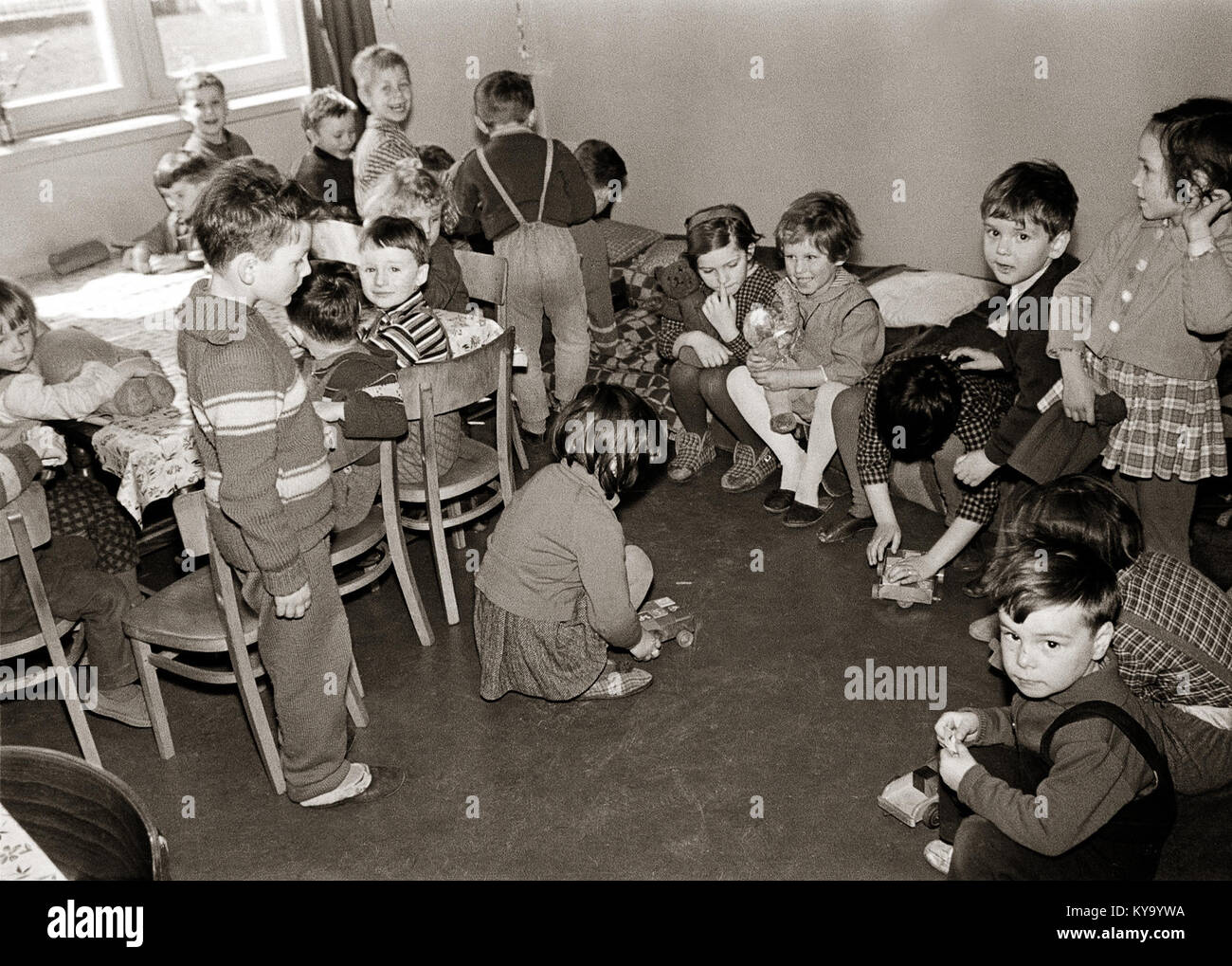 Questa fotografia raffigura un asilo per bambini a Studenci nel 1964, che mostra l'edificio, il parco giochi e i bambini durante le attività quotidiane. Foto Stock