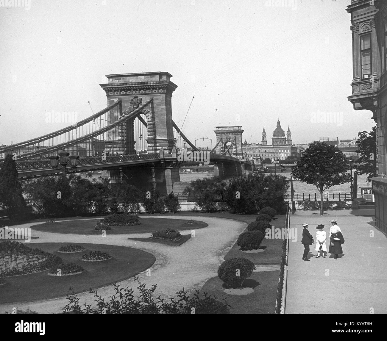 Una fotografia storica che mostra il Ponte delle catene (Lánchíd) di Budapest visto da Piazza Clark Ádám, con la basilica di Santo Stefano visibile in lontananza. L'immagine mette in risalto i principali punti di riferimento della capitale ungherese. Foto Stock