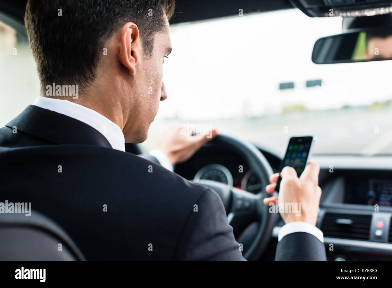 L'uomo texting durante la guida in auto Foto Stock