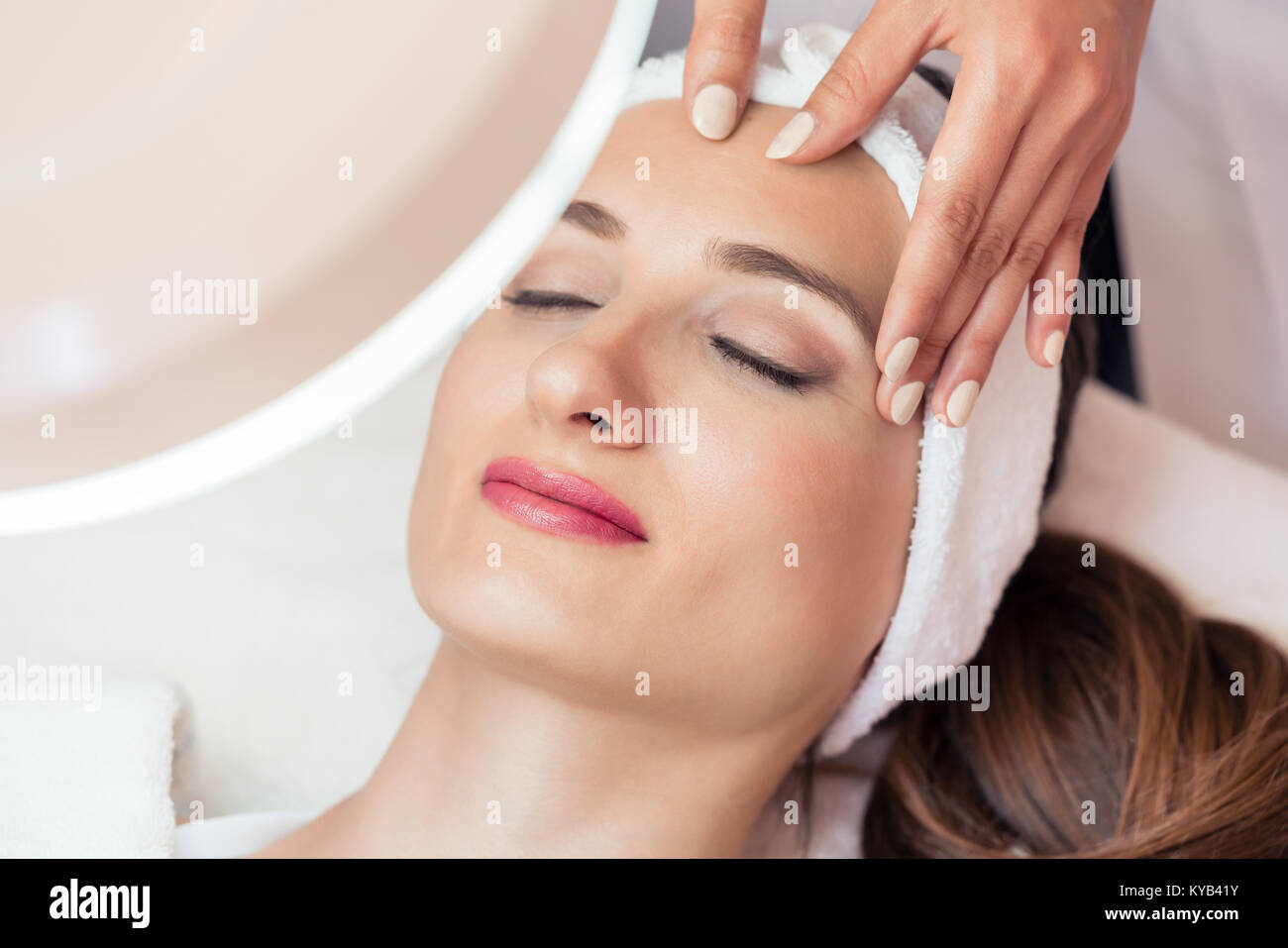 Rilassata donna sorridente sotto i vantaggi di anti-invecchiamento ma per il viso Foto Stock