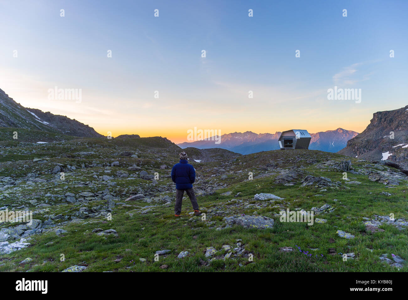 Una persona che guarda alba colorata in alto nelle Alpi. Ampio angolo di visione da sopra con incandescente picchi di montagna in background. Avventura estate Foto Stock