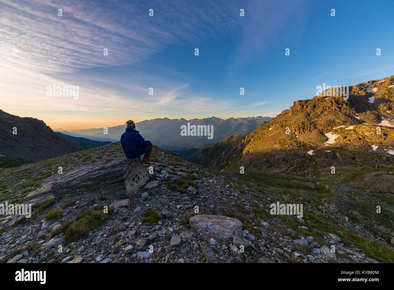 Una persona che guarda alba colorata in alto nelle Alpi. Ampio angolo di visione da sopra con incandescente picchi di montagna in background. Avventura estate Foto Stock