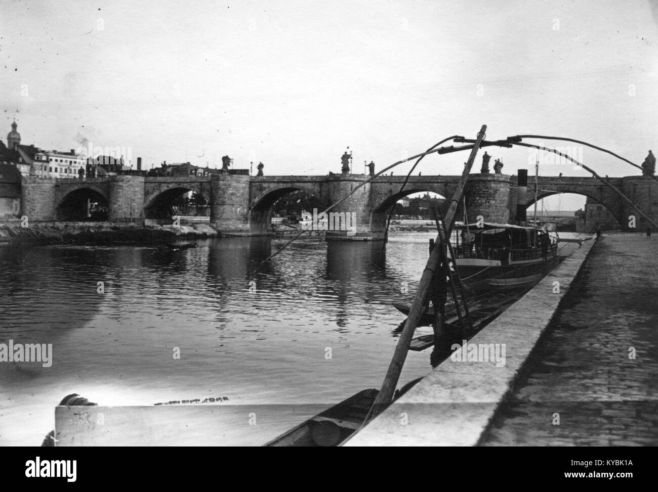 Fotografia storica del Ponte Vecchio principale a Würzburg, Germania, che mostra archi in pietra e statue che si estendono lungo il fiume meno, un esempio di architettura barocca del ponte. Foto Stock