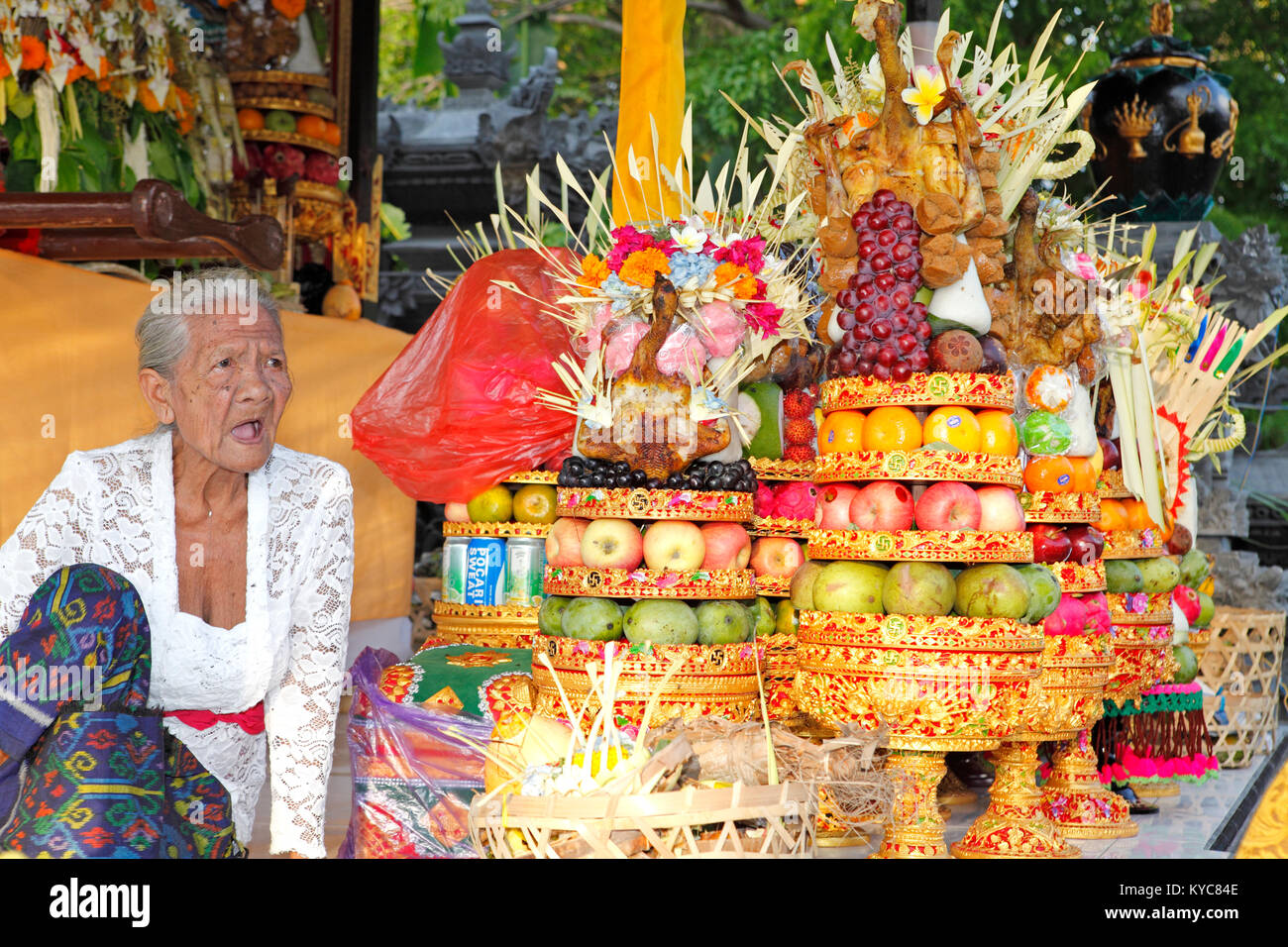 Anziana donna balinese seduto accanto a torri del tempio, le offerte di Lovina, Bali, Indonesia Foto Stock