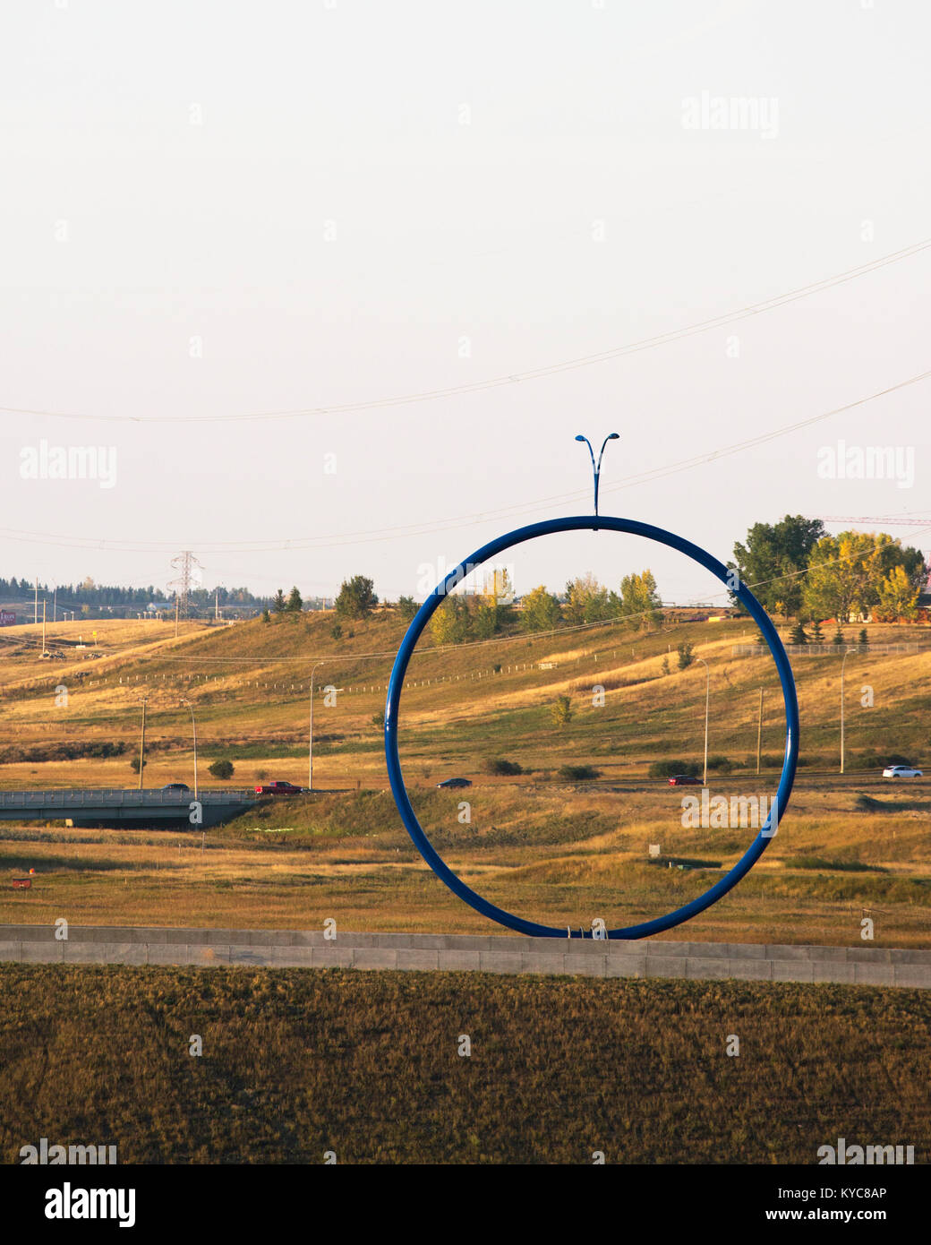 "Viaggiare leggeri' scultura, un grande cerchio blu con luce standard sulla parte superiore una controversa arte pubblica installazione accanto a un'autostrada in Calgary Foto Stock