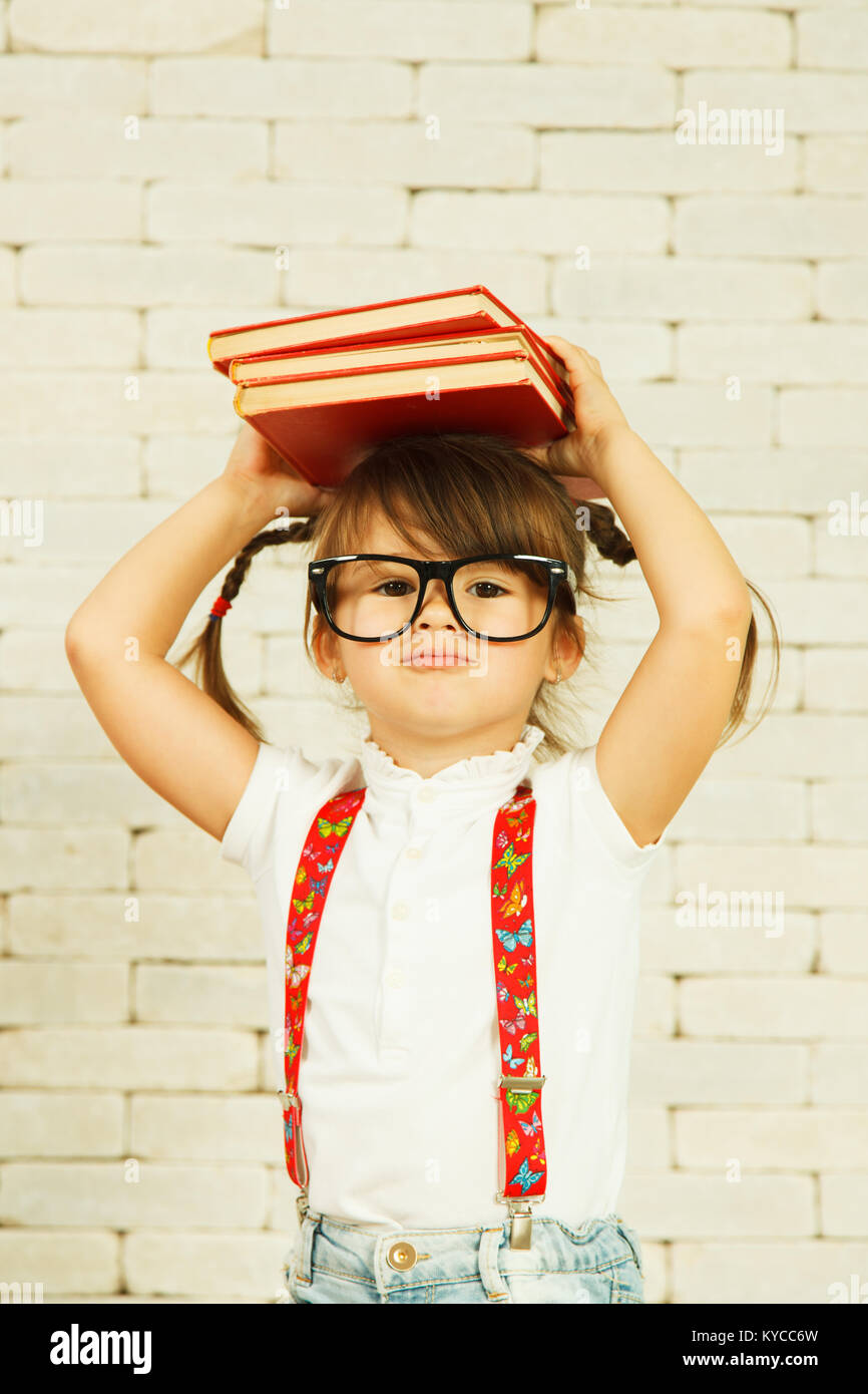 Preschooler ragazza con libri sulla testa Foto Stock