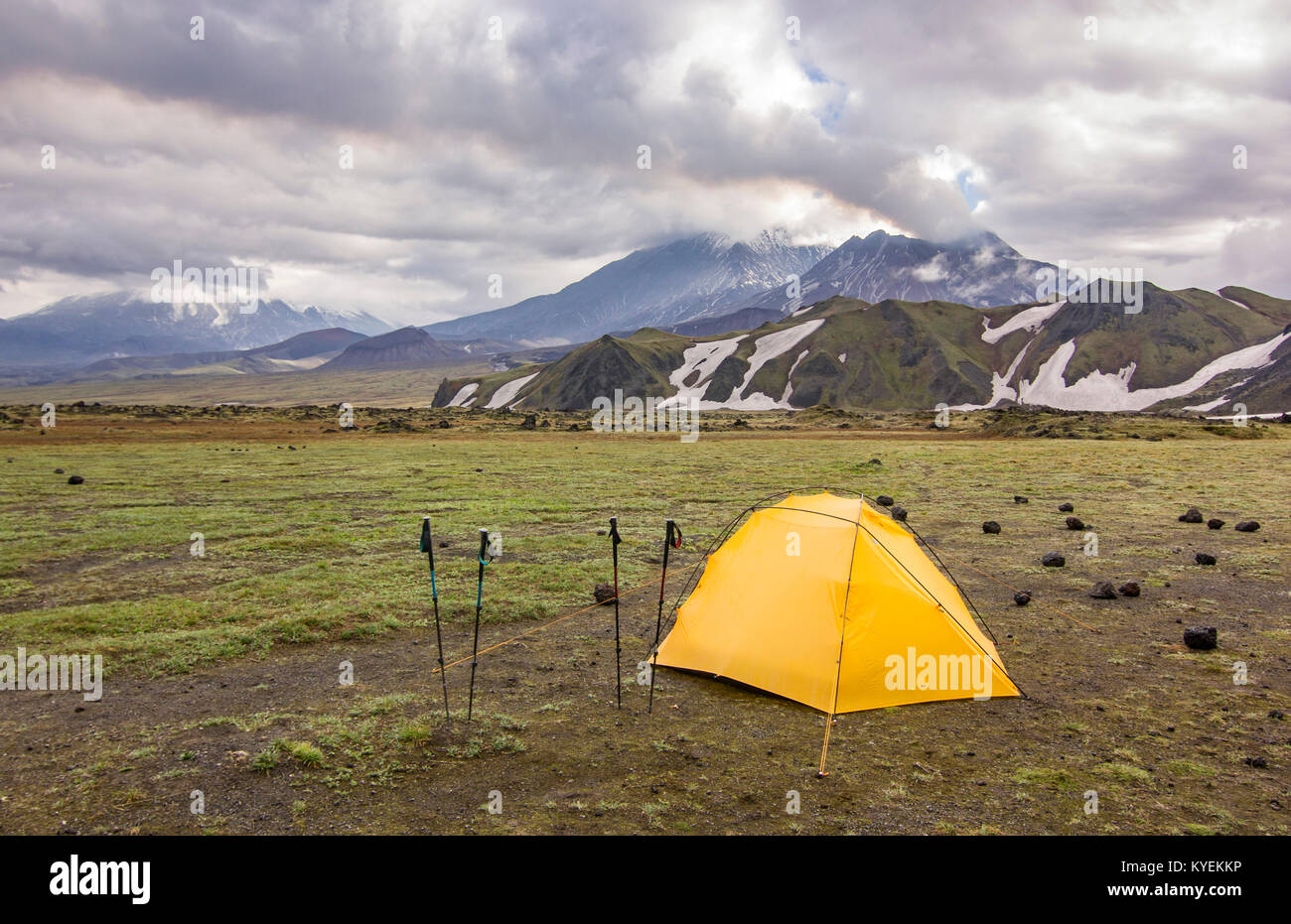 Tenda giallo su verde campo nei pressi di vulcani attivi della Kamchatka con le nuvole in cielo al tramonto Foto Stock