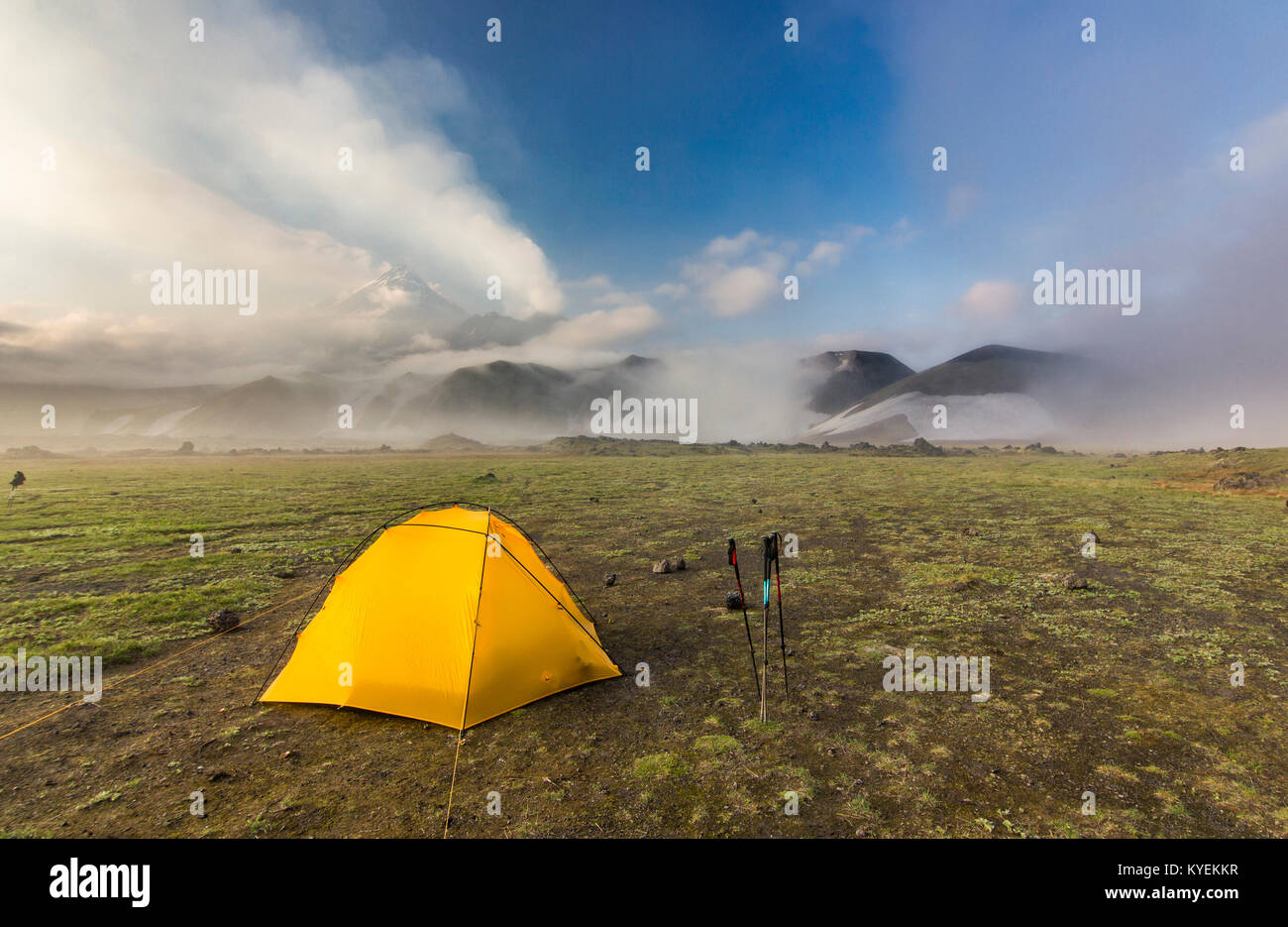 Tenda giallo su verde campo nei pressi di vulcani attivi della Kamchatka con le nuvole in cielo al tramonto Foto Stock