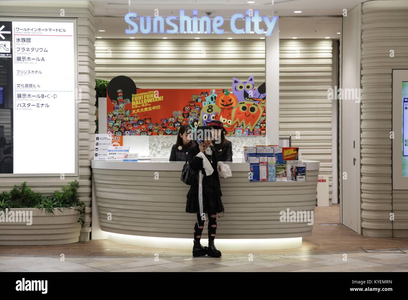 Una donna si trova nei pressi di un banco informazioni ed effettua una chiamata telefonica all'interno di Ikebukuro Sunshine City, un complesso di shopping nel reparto di Ikebukuro, Toshima di Tokyo, Giappone, 16 ottobre 2017. () Foto Stock