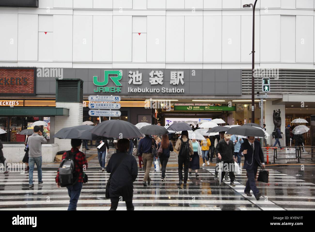 Persone con ombrelloni attraversare una strada verso la Stazione di Ikebukuro in un giorno di pioggia, una stazione ferroviaria nel quartiere di Ikebukuro di Tokyo, Giappone, 16 ottobre 2017. () Foto Stock