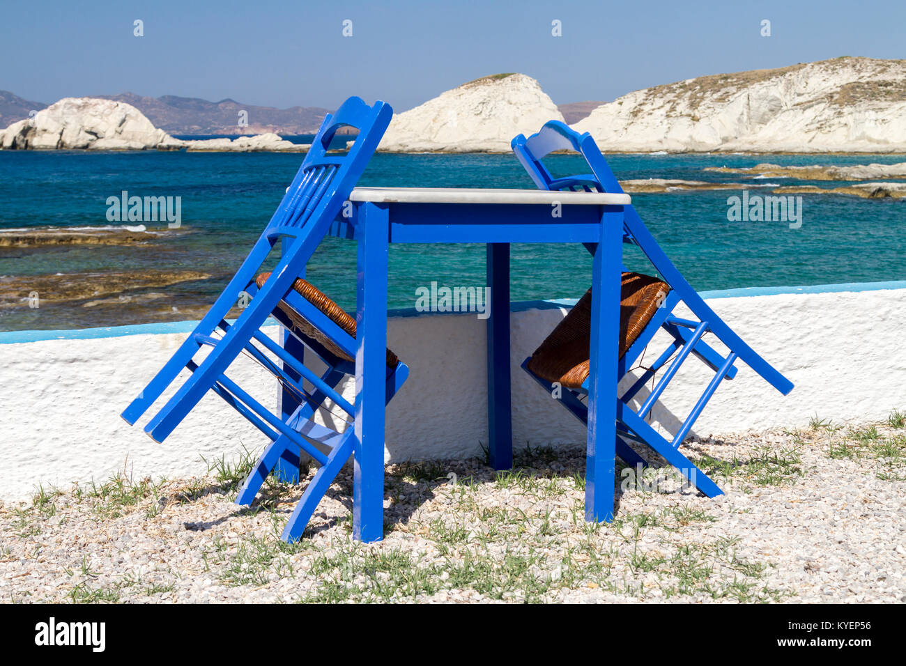 Taverna chiuso, blu dipinto di tavolo e sedie dal mare con una vista delle Cicladi in background Foto Stock