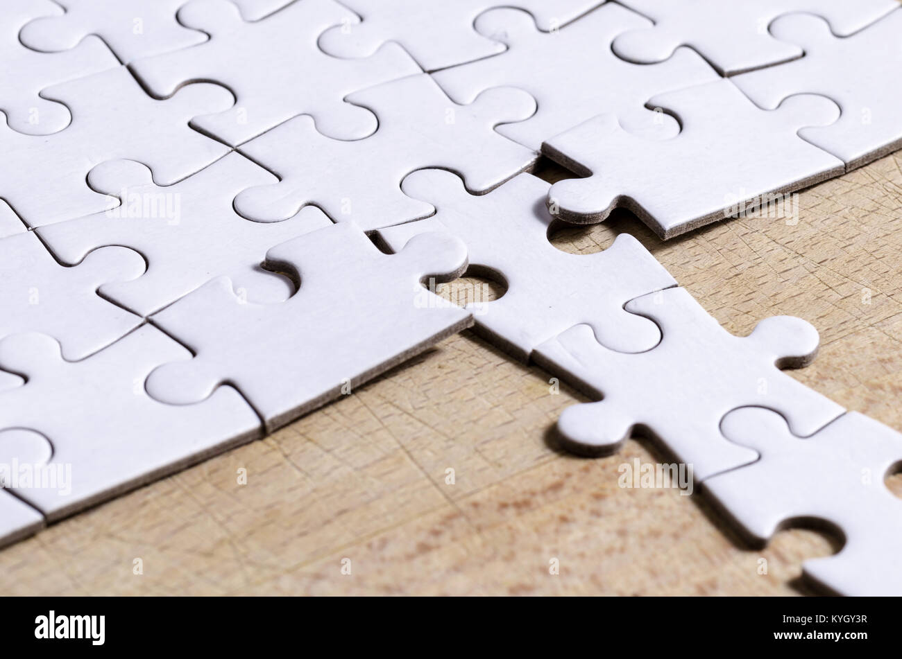 Bianco/jigsaw puzzle con una riga nella posizione sbagliata su un tavolo di legno sfondo, simbolo di problem solving e nuova visione Foto Stock