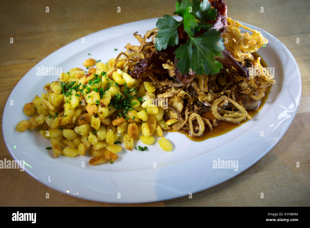 Lo Spaetzle servita con carni di maiale e deep-cipolle fritte in Nuremberg, Germania. Il piatto è un tradizionale del sud della specialità tedesche. Foto Stock